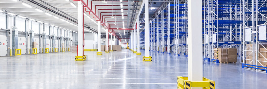 Empty huge distribution warehouse with high shelves and loading gates