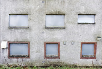 Obraz na płótnie Canvas Abandoned building metal sheet board over windows dull grey dirty wall