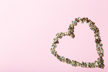 Round colorful sequins in heart shape on pink background