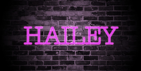 first name Hailey in pink neon on brick wall