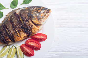 Fried fish dorado with lime , tomatoes and spinach