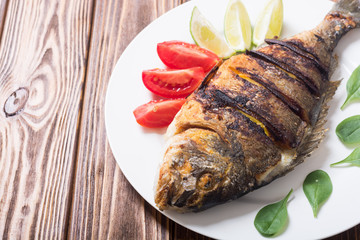 Fried fish dorado with lime , tomatoes and spinach