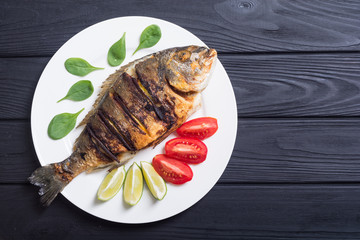 Fried fish dorado with lime , tomatoes and spinach