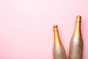 Decorated champagne bottles on pink background