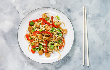 Stir fry noodles with vegetables and shrimps on concrete background.