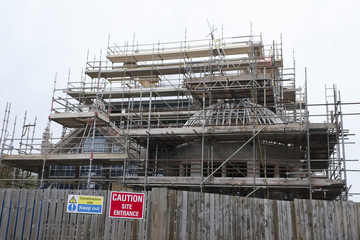 Scaffolding around new construction site and wooden fence caution entrance sign
