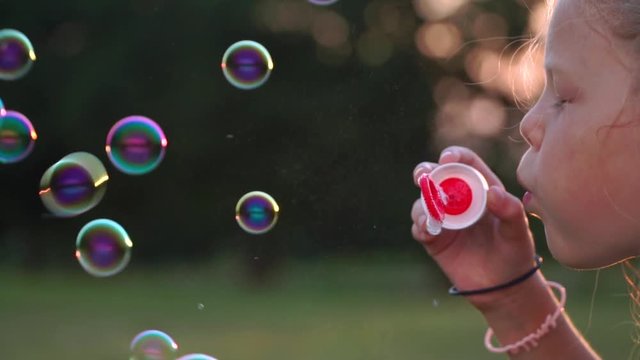 little blond girl blowing bubbles