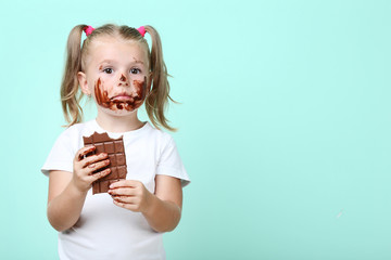 Happy little girl eating chocolate on mint background