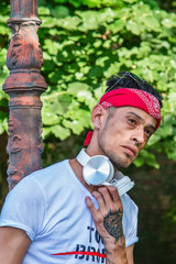 Extravagant (hipster) male model in nature. The guy poses in front of an old street light.