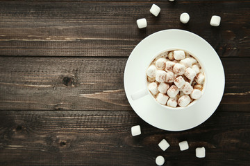 Cappuccino with marshmallows in cup on wooden table