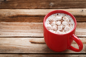 Cappuccino with marshmallows in red cup on wooden table