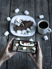 A piece of cake and a cup of coffee on a wooden table,