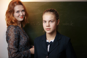Smiling elderly teacher near the chalkboard asking student at the math lesson