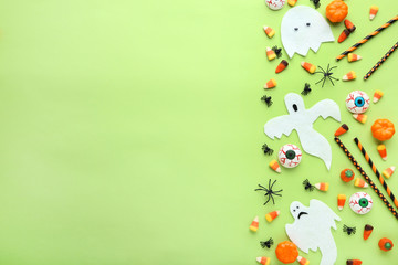 Halloween candies with paper decorations on green background