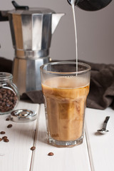 Coffee in a tall glass with cream poured over