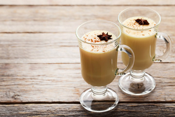 Eggnog in glasses with star anise on wooden table
