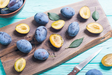Fresh plums in bowl on wooden table