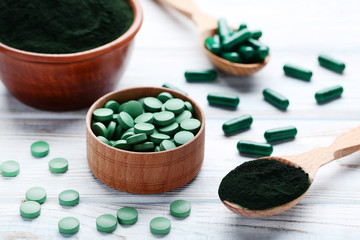 Spirulina powder and tablets on wooden table