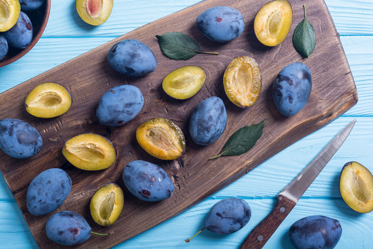 Fresh plums in bowl on wooden table