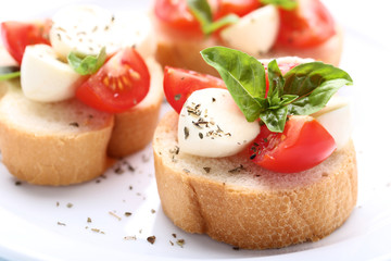 Bruschetta with mozzarella, tomatoes and basil leafs