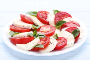 Mozzarella, tomatoes and basil leafs on wooden table