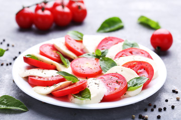 Mozzarella, tomatoes and basil leafs on grey wooden table