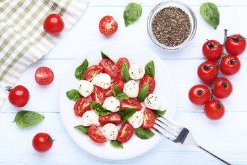 Mozzarella, tomatoes and basil leafs on wooden table
