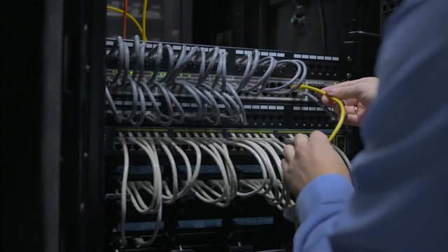 IT engineer opens the server cabinet and plug out network cable into the switch