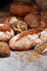Different kinds of bread and bread rolls on board from above. Kitchen or bakery