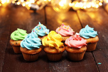 Tasty cupcakes on christmas winter background. Birthday cupcake in rainbow colors.