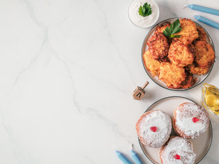 Jewish holiday Hanukkah concept and background. Hanukkah food, oil, candles and traditional spinnig dreidl. Top view or flat lay. Copy space for text. © fascinadora