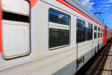 Local Train Arriving at Platform on Railway Station. Summer Day Perspective View of Old Gray and Red Train with Doors Closed and Sky Reflecting on the Windows. 