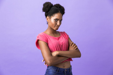 Photo of offended or naughty african american woman standing with arms folded, isolated over violet...