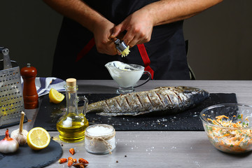 Chef squeezes garlic of making fish sauce. Hands in the process of cooking fish. Top view, place for text