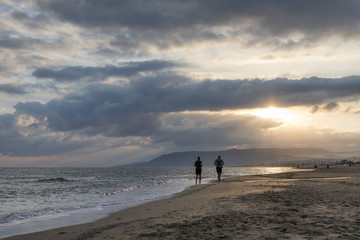 couple running on the beach at sunrise