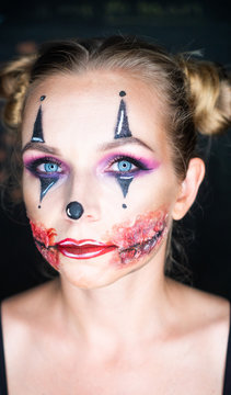 Closeup face of woman with creepy Halloween clown makeup looking into the camera. Creative, artistic, Halloween concept