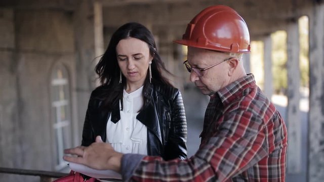 Woman engineer and superintendent in the helmet to discuss the necessary materials and technical resources to continue construction.