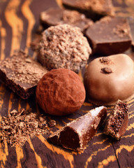 Handmade chocolate candies and pieces of chocolate on wooden background