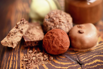 Handmade chocolate candies and pieces of chocolate on wooden background