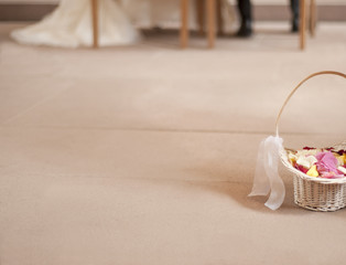 Korb mit Blütenblättern auf dem Boden hinter dem sitzenden Brautpaar / Basket with petals on the floor behind the sitting bride and groom
