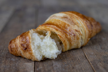 Tasty well-baked croissant on a wooden kitchen table. Light bread prepared for breakfast.