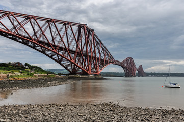 Famous Forth Bridge in Edinburgh, Scotland with a small boat in background. 