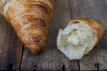 Tasty well-baked croissant on a wooden kitchen table. Light bread prepared for breakfast.