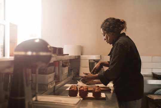 Baker cutting brownies at the counter of a commercial kitchen