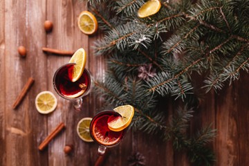 Christmas and New Year decor. Two cups of mulled wine with oranges stand on a wooden table covered...