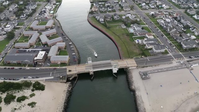 Aerial drone shot at dusk over a bridge with a boat heading out into the ocean off the coast of Belmar, New Jersey.