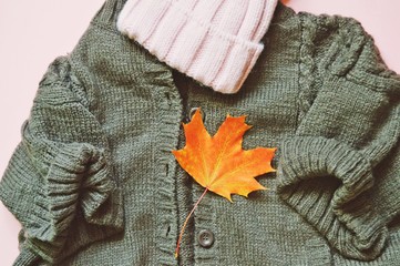 Flat lay brown knitted sweater and pink woolen hat. Cozy autumn outfit. Warm women's clothes