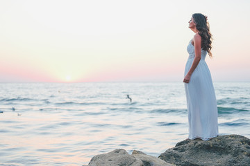 Romantic feminine woman in white dress waiting at the shore