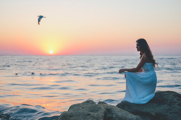 Fototapeta na wymiar Romantic feminine woman in white dress waiting at the shore