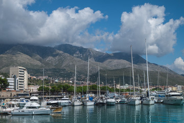 Fototapeta na wymiar Boats and yachts in the harbor in Formia, with mountains and clouds in the background. 